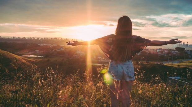 woman-stands-on-mountain-over-field-under-cloudy-sky-at-847483